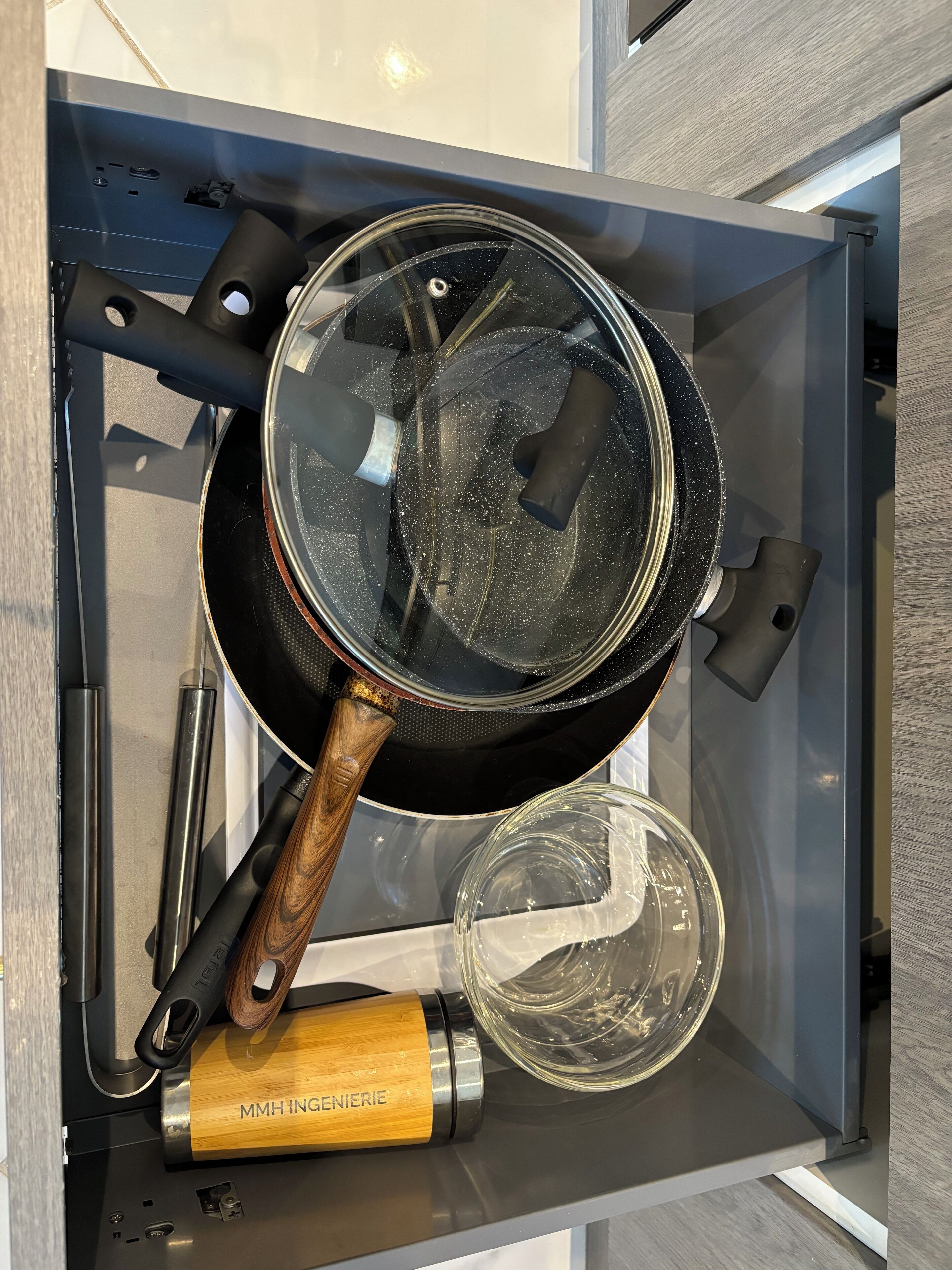 Eine Küchenschublade mit einer Bratpfanne, einem Pfannenwender und einem Glasbehälter.