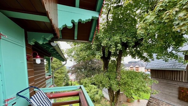 A wooden deck with a striped chair, a small table, and a hanging light fixture.