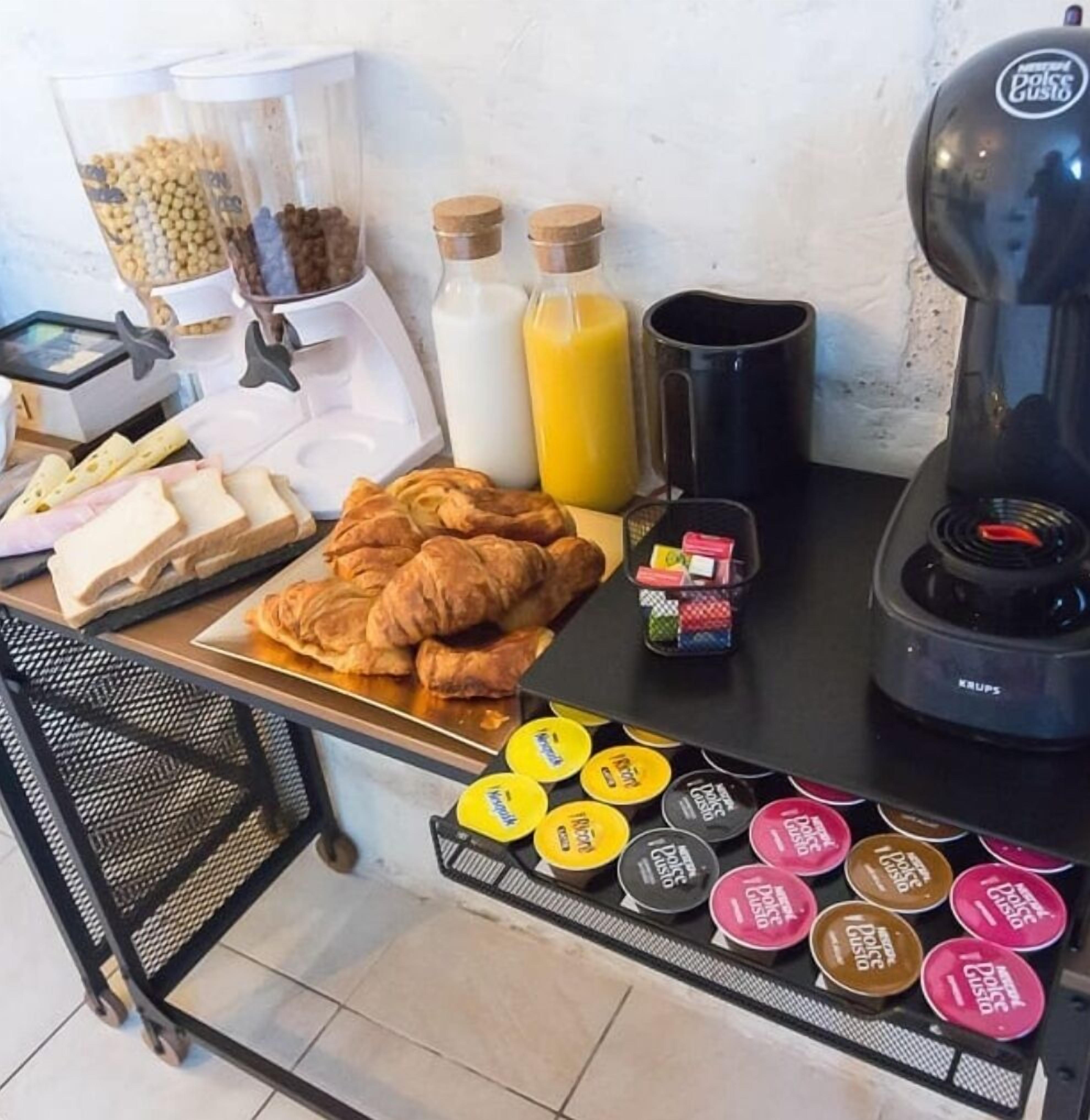 Un buffet de petit-déjeuner comprenant des croissants, du fromage, du lait, du jus d’orange, du café et divers condiments.