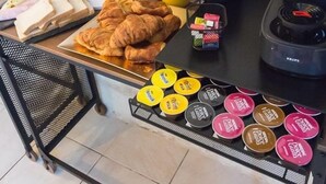 Un buffet de petit-déjeuner comprenant des croissants, du fromage, du lait, du jus d’orange, du café et divers condiments.
