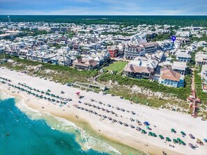 An aerial view of a coastal residential area with beachfront properties, a sandy beach, and a water tower in the distance.