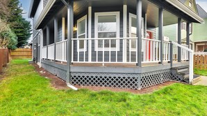 A house with a covered porch, a fenced yard, and a wooden deck.