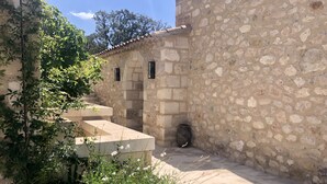 Un bâtiment en pierre avec un toit recouvert de tuiles, une petite fenêtre et une porte.