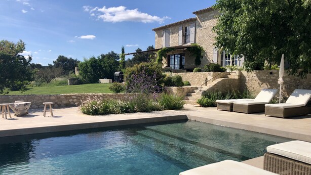 Une piscine avec des chaises longues et un mur en pierre.