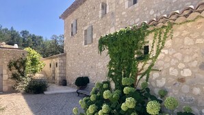 Un bâtiment en pierre dont les murs sont recouverts de lierre et qui possède une cour intérieure en gravier.