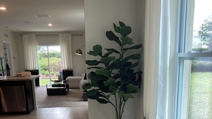 A spacious living area with a large window, a potted plant, and a kitchen in the background. - Beautiful Lake View House with 3/2 near Disney, Universal, Sea World and more! (Sparta)