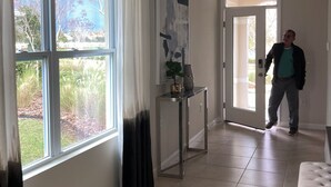 A spacious room with large windows, a modern console table, and a view of the outdoors. - Beautiful Lake View House with 3/2 near Disney, Universal, Sea World and more! (Sparta)