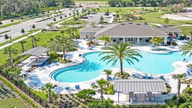 A resort with a large swimming pool, lounge areas, and a building with a flat roof. - Beautiful Lake View House with 3/2 near Disney, Universal, Sea World and more! (Sparta)