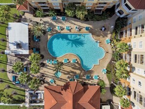 An aerial view of a hotel with a central swimming pool surrounded by lounge chairs and palm trees. - Suite · The Point Lux Suite, close to Universal (Orlando)
