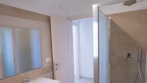 A modern bathroom with a white vanity, a large mirror, and a glass-enclosed shower area. - North Shell (Cala Gonone)
