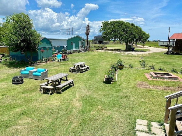 A grassy outdoor area with picnic tables, a small play structure, and a shed.