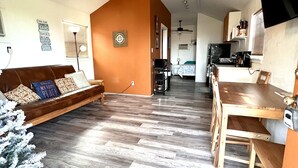 Ampla sala de estar com piso de madeira, ventilador de teto, sofá e mesa de jantar com cadeiras.