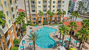 A rooftop pool surrounded by palm trees and lounge chairs, with a view of adjacent buildings. - Studio · The point Studio 10 min Universal (Orlando)