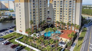 A high-rise hotel with multiple floors, a swimming pool, and a parking lot. - Studio · The point Studio 10 min Universal (Orlando)