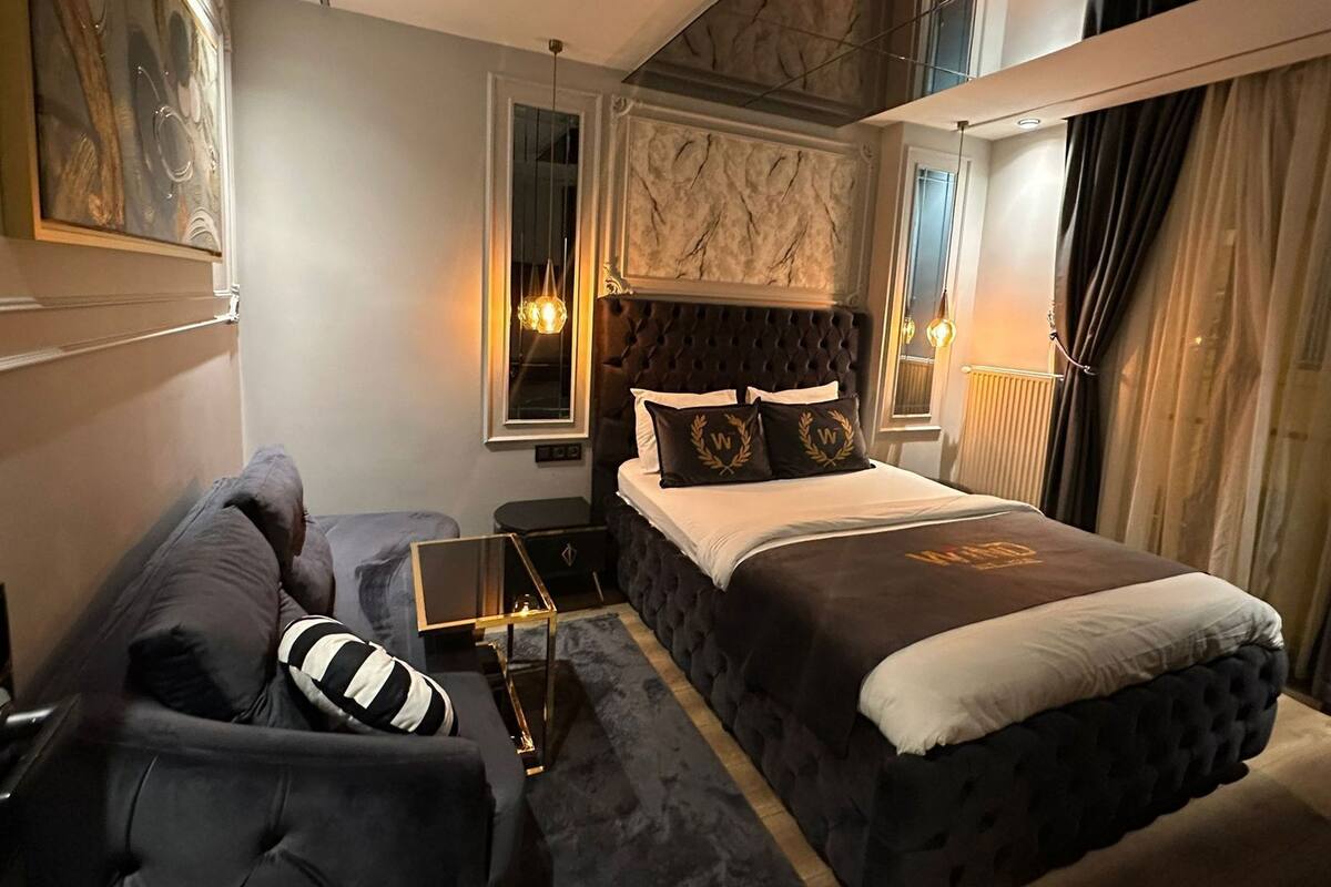 A modern bedroom with a large bed, a sofa, a small table, and a mirror.