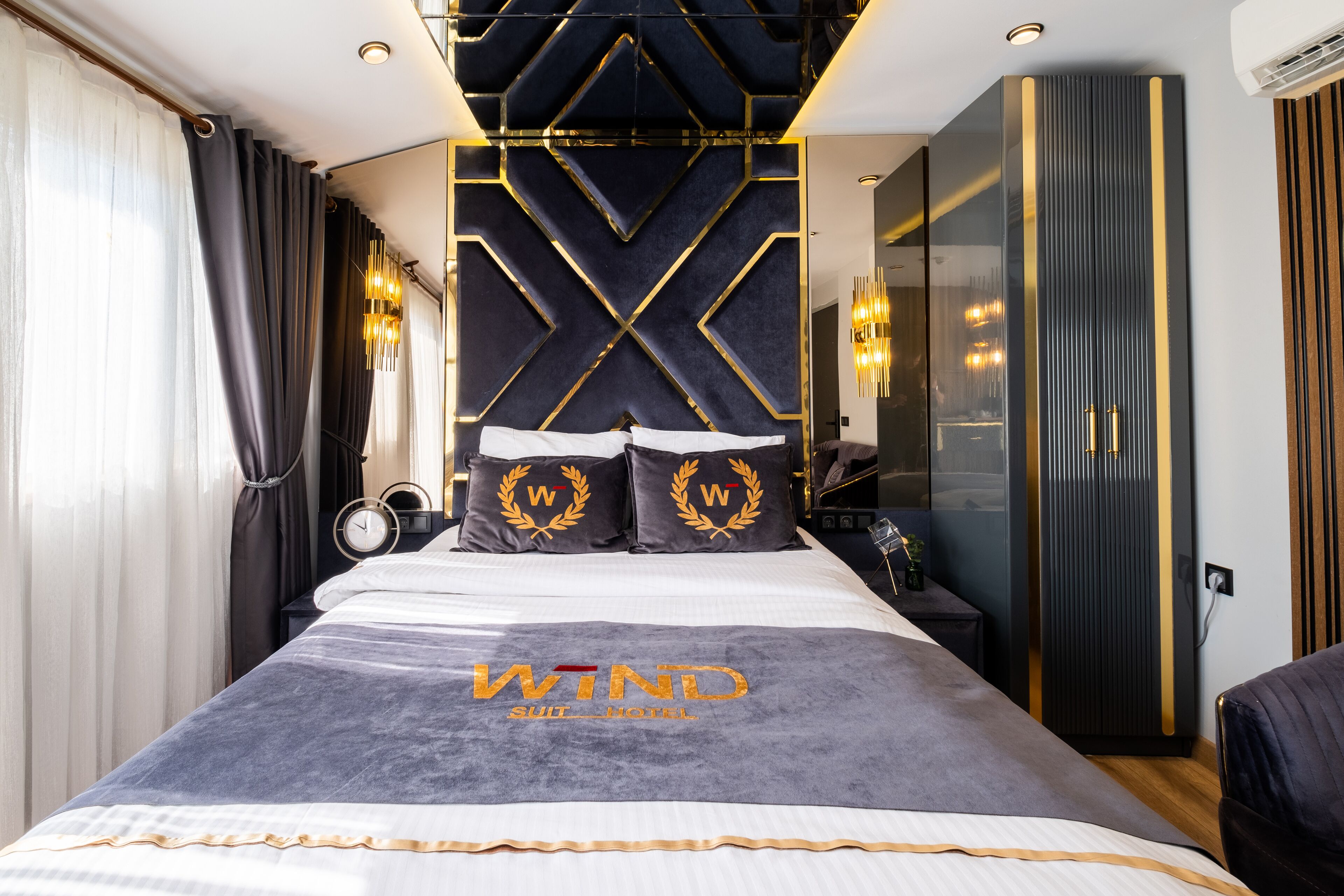 A modern hotel room with a large bed, a wall-mounted TV, and a wardrobe.