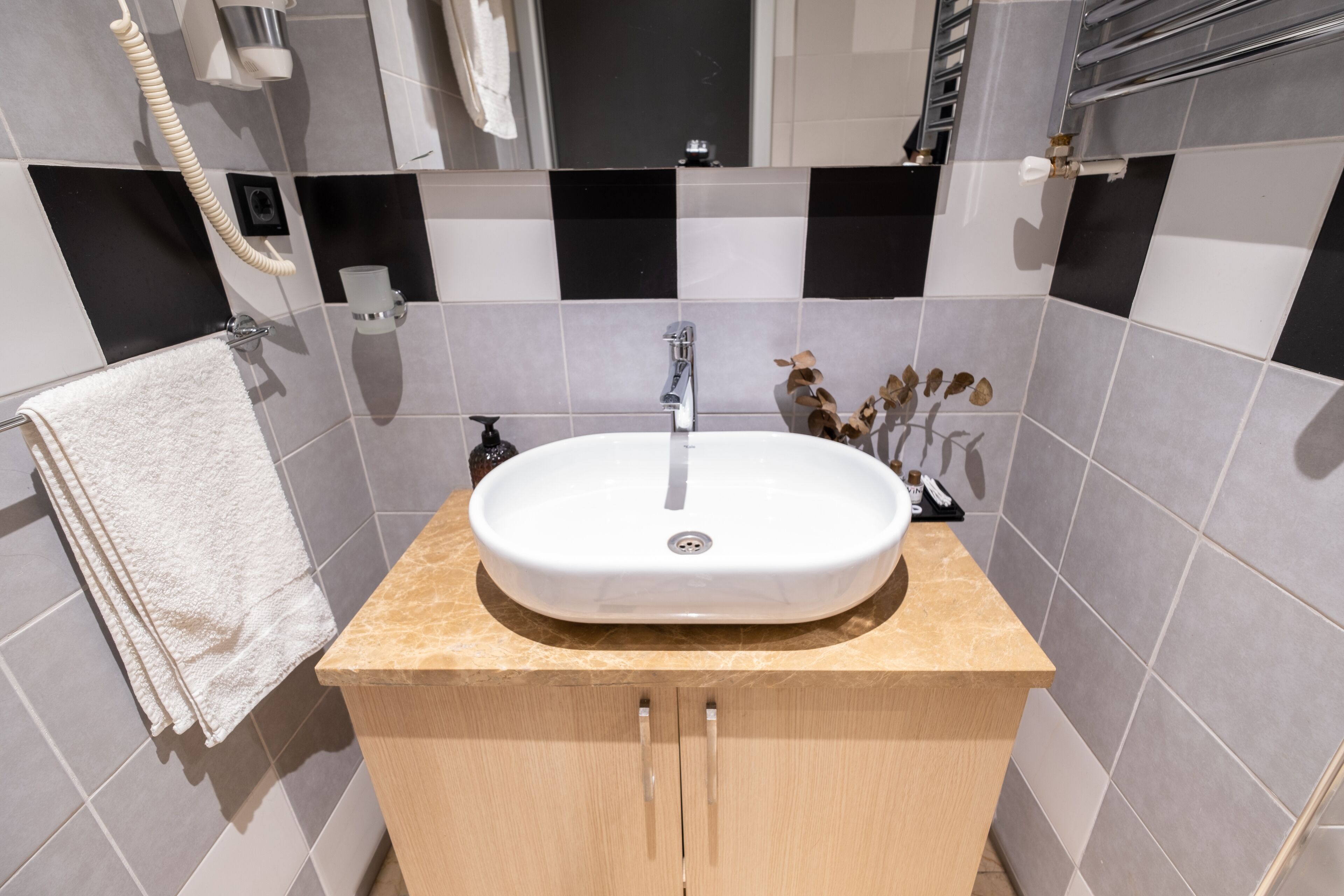 Un bagno con un lavandino bianco, un piano di lavoro color beige e un porta asciugamani.