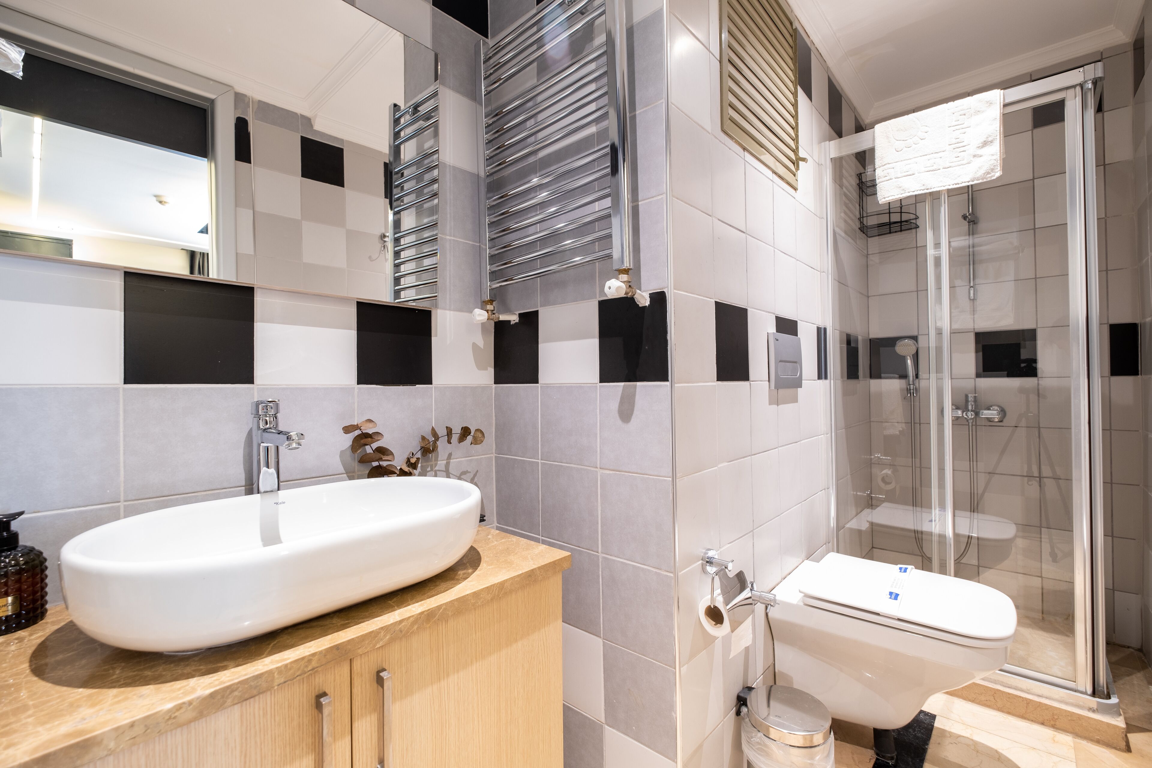 Un baño moderno con un lavamanos grande de color blanco, un inodoro y una ducha con cerramiento de vidrio.