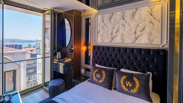Une chambre d’hôtel moderne avec un grand lit, une vue sur la ville et un balcon.