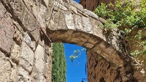 Un estrecho sendero de piedra que atraviesa un arco, con un cartel que indica 'Villa Area' a la izquierda.