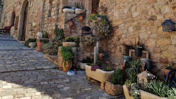 Una estrecha calle empedrada flanqueada por edificios de piedra con puertas y ventanas de arco.