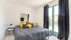 Un dormitorio con una cama, dos mesitas de noche, un espejo y cortinas negras.