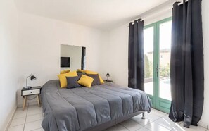 A bedroom with a bed, two bedside tables, a mirror, and black curtains.