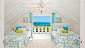 A bedroom with two beds, a view of the ocean, and a ceiling fan. - Bahama Mama 5 Bedroom Home (Governor's Harbour)