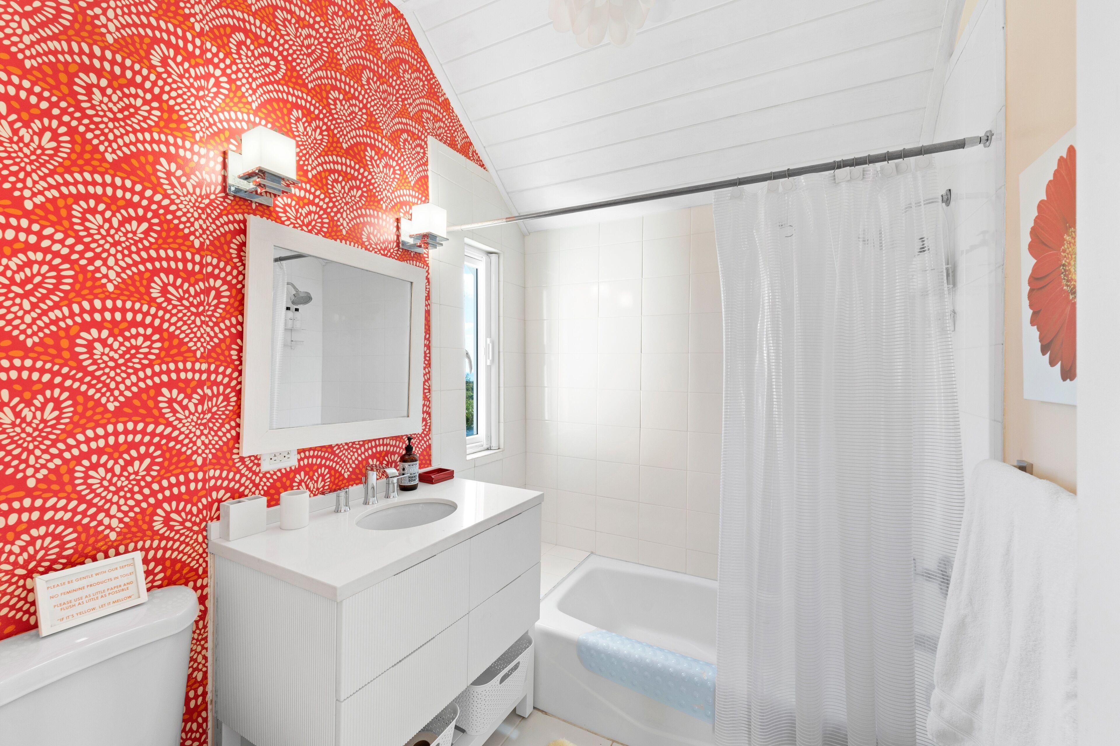 A bathroom with a white vanity, a large mirror, a bathtub, and a shower curtain.
