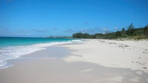 A beach with clear turquoise water, white sand, and sparse vegetation. - Bahama Mama 5 Bedroom Home (Governor's Harbour)