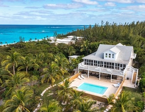 A large house with a pool, surrounded by palm trees and a view of the ocean. - Bahama Mama 5 Bedroom Home (Governor's Harbour)