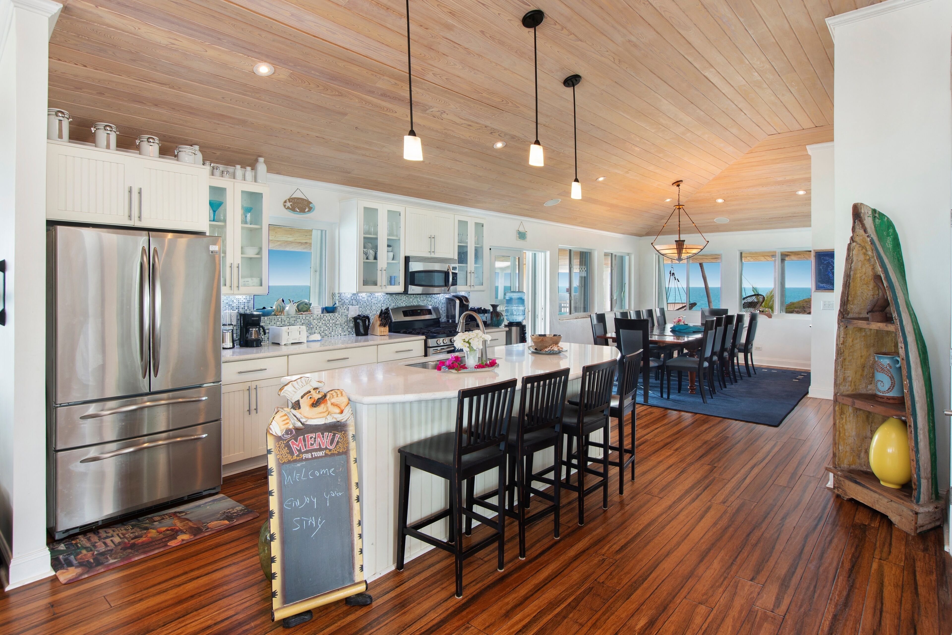A modern kitchen with a central island, stainless steel appliances, and a view of the ocean.