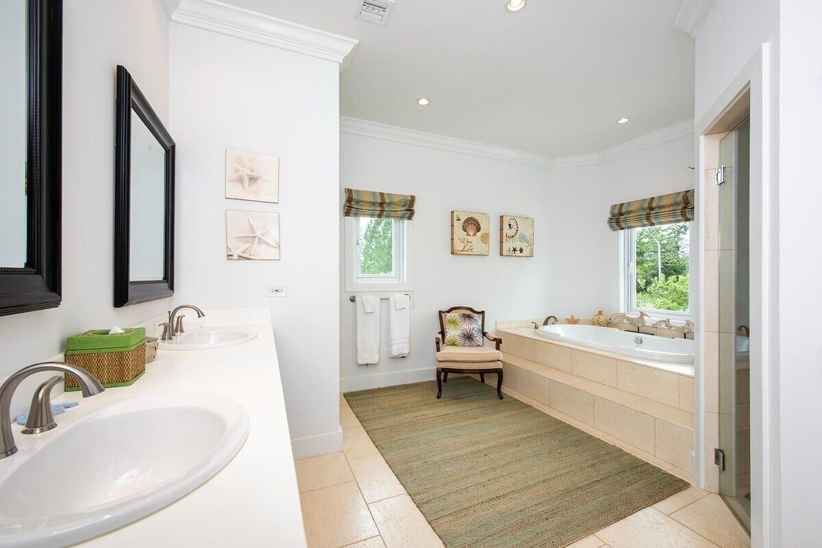 Een badkamer met twee wastafels, een bad en een stoel.