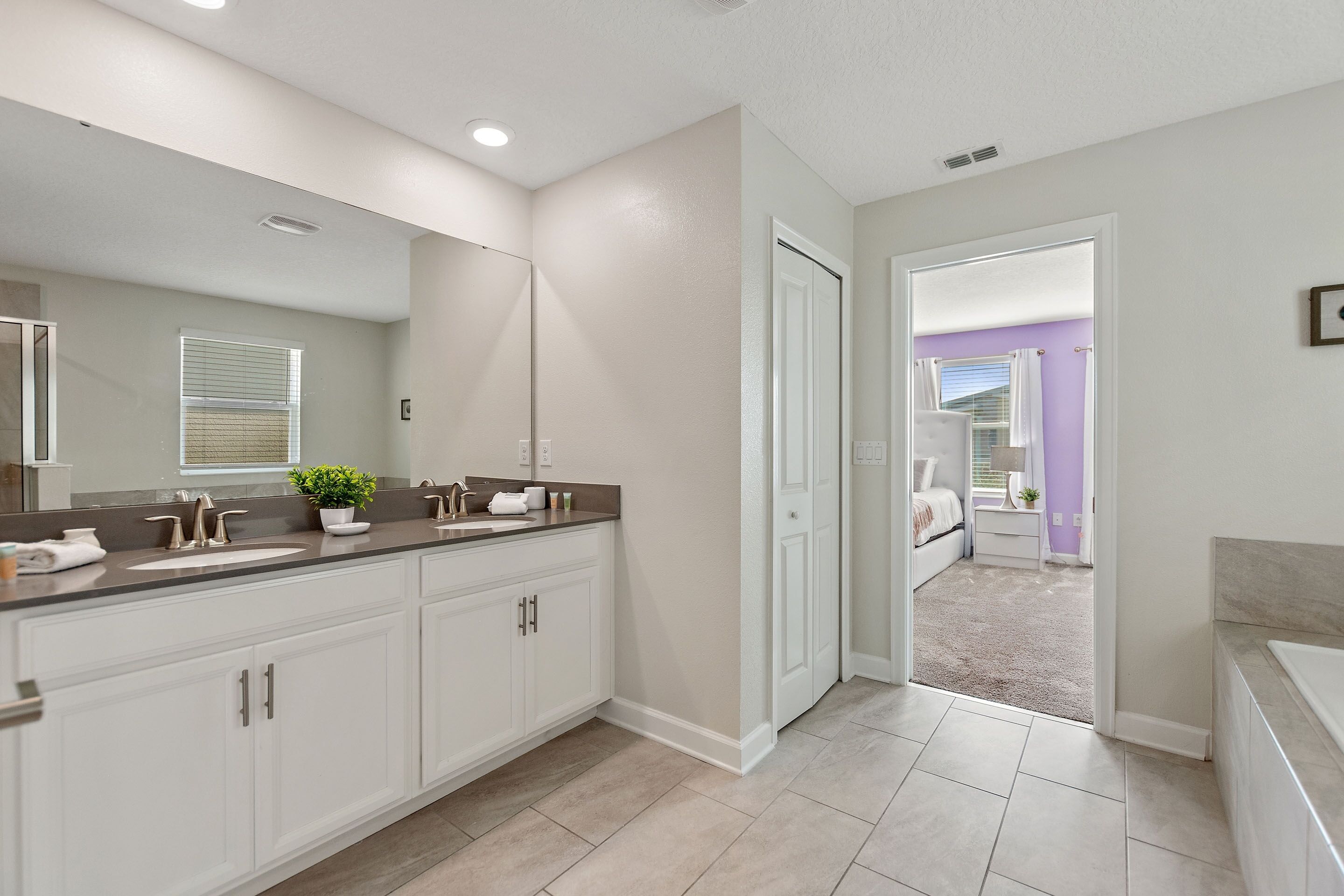 A modern bathroom with a large mirror, two sinks, and a walk-in shower.