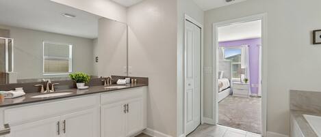 A modern bathroom with a large mirror, two sinks, and a walk-in shower.