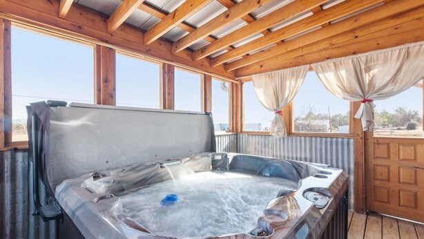 A hot tub with a wooden ceiling and large windows.