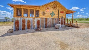 A rustic wooden building with a corrugated metal exterior, a wooden porch, and decorative sun motifs.