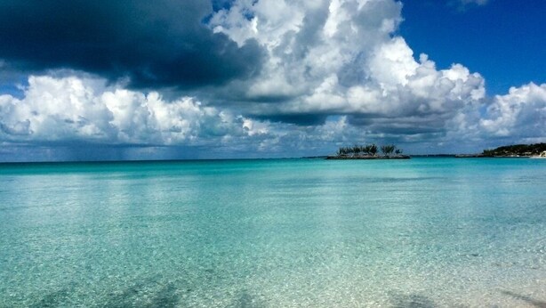 A beach with clear turquoise water and a large cloud formation in the sky. - Moonflower 4 Bedroom Home (Gregory Town)