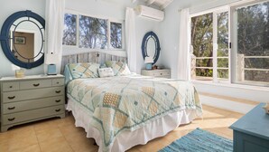 A bedroom with a bed, dresser, and large windows. - Moonflower 4 Bedroom Home (Gregory Town)