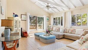 A spacious living area with a glass coffee table, a sofa set, and a ceiling fan. - Moonflower 4 Bedroom Home (Gregory Town)