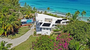 A modern house with a pool, surrounded by lush greenery and a view of the ocean.