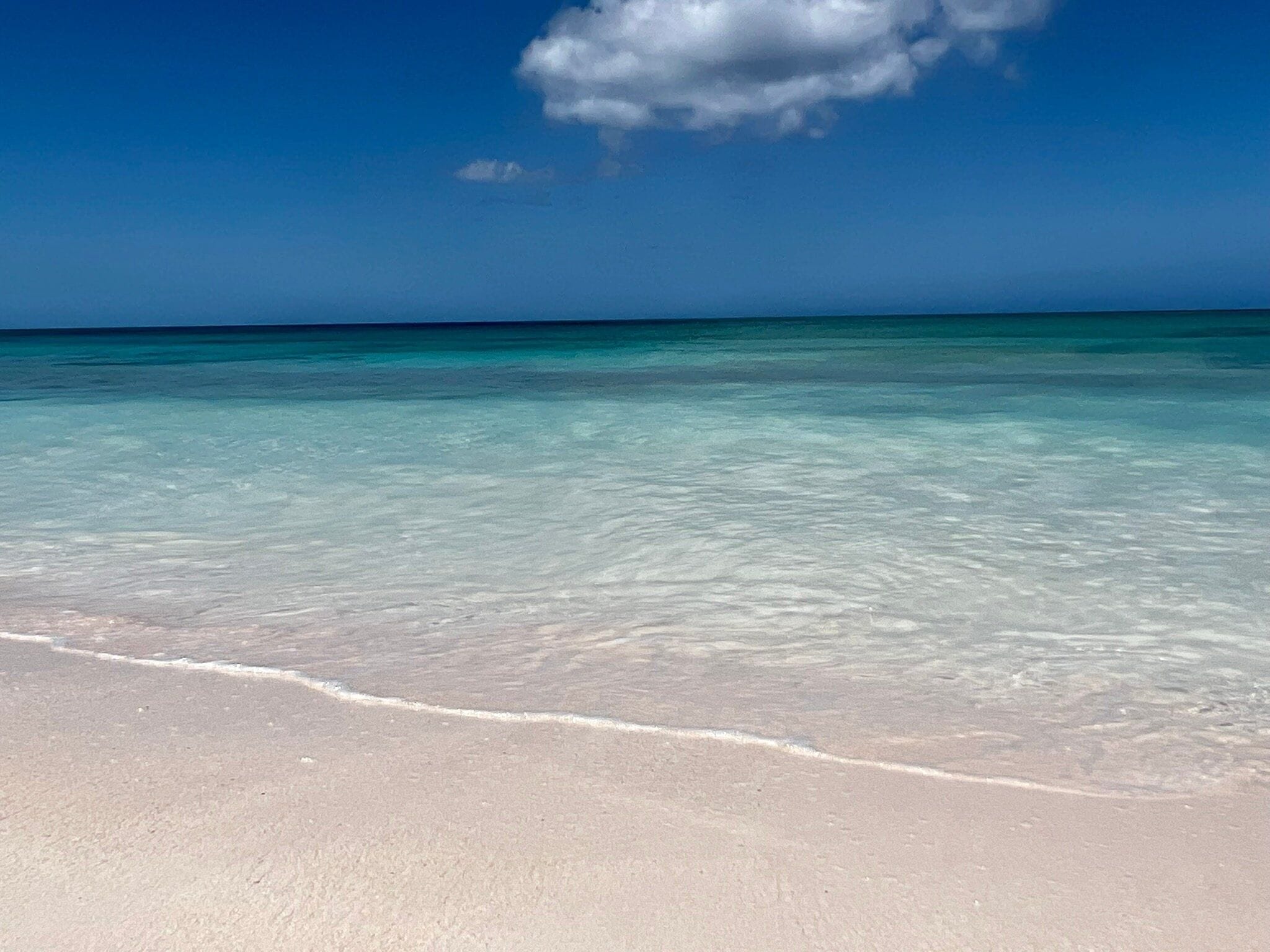 Een strand met helder turquoise water en een zandstrand.