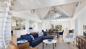 A spacious living area with a high ceiling, a dining area, and a kitchen visible through an open layout. - Buttonwood Reserve Main Lodge 1 Bedroom Home (James Cistern)