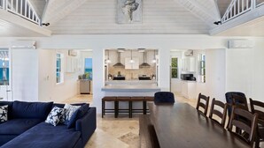 A spacious living area with a dark blue sofa, a wooden dining table, and a kitchen in the background. - Buttonwood Reserve Main Lodge 1 Bedroom Home (James Cistern)