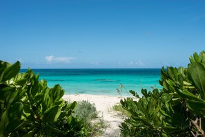 A beach with clear turquoise water and a sandy shore, surrounded by lush green foliage. - Poponi House 2 Bedroom Home (North Palmetto Point)
