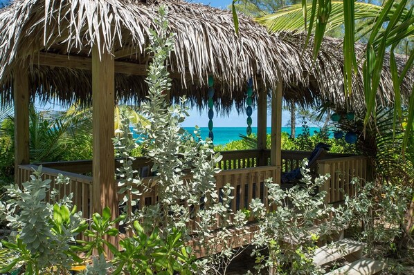 A wooden gazebo with a thatched roof overlooking a beach. - Poponi House 2 Bedroom Home (North Palmetto Point)