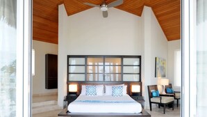A bedroom with a large bed, a ceiling fan, and a view through a glass door. - Sky Beach Club Bungalow 1 Bedroom Cabin (Governor's Harbour)