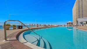 A swimming pool with a curved edge, a metal railing, and a paved walkway.