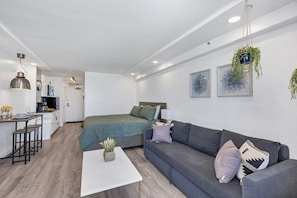 Um apartamento moderno com cozinha, sala de jantar, sala de estar com sofá e mesa de centro, e uma cama.