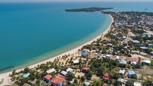 An aerial view of a coastal area with a beach, houses, and boats.